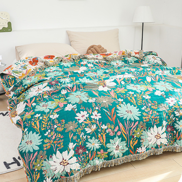 Wendbare Steppdecke aus Baumwollgaze mit leuchtendem Blumenmuster und Quasten