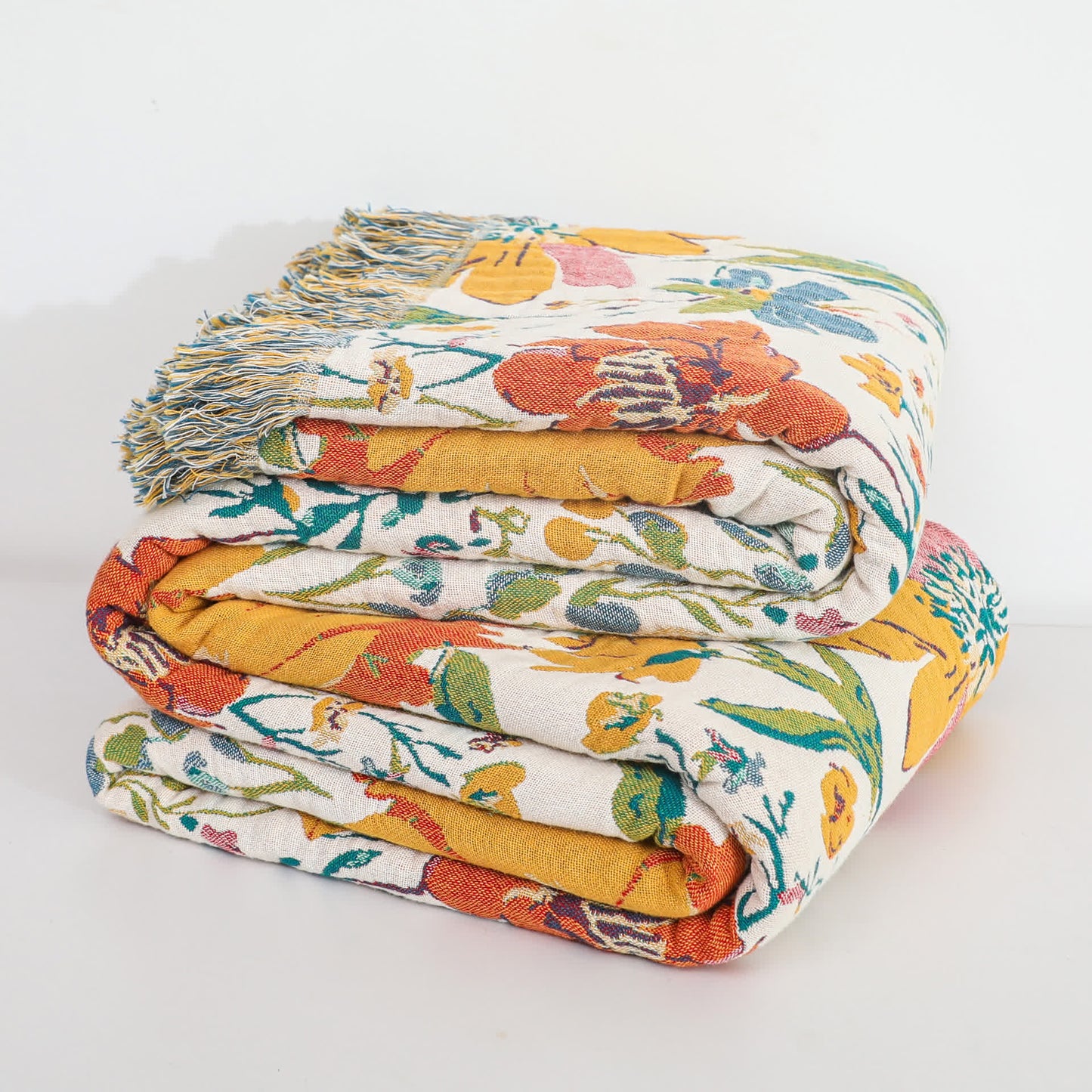 Wendbare Steppdecke aus Baumwollgaze mit leuchtendem Blumenmuster und Quasten