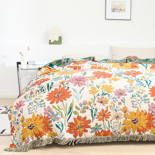 Wendbare Steppdecke aus Baumwollgaze mit leuchtendem Blumenmuster und Quasten